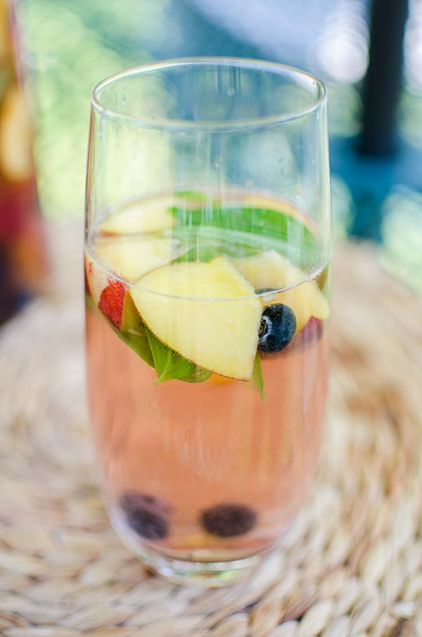 Peach sangria with blueberries, basil and rose for a crowd for a refreshing summer cocktail. | livinglou.com