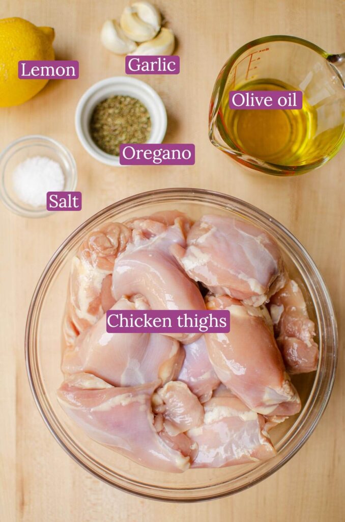 Ingredients for Greek chicken marinade in glass bowls on a wooden board.