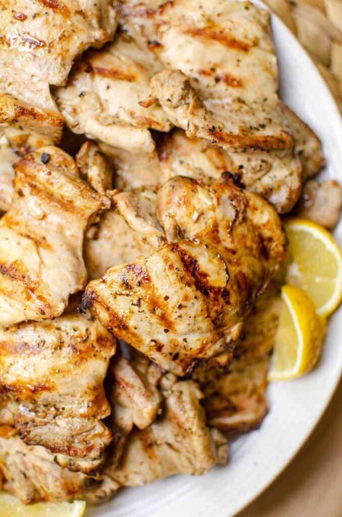 Closeup of chicken on a platter with lemon slices.