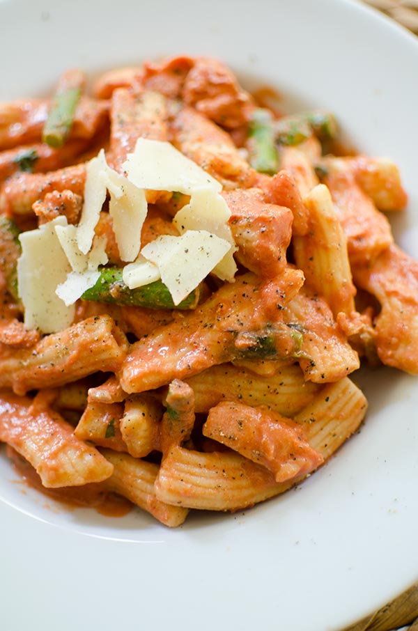 Pasta with salmon and asparagus in a creamy rose sauce in a white bowl