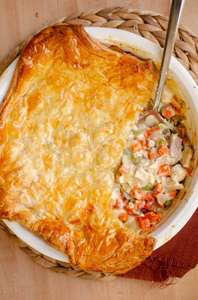 Turkey pot pie in a pie plate, with a serving missing.