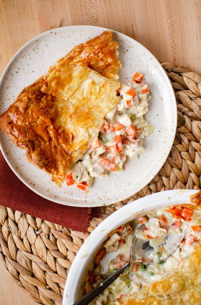 A serving of pot pie on a plate next to the full pie. 