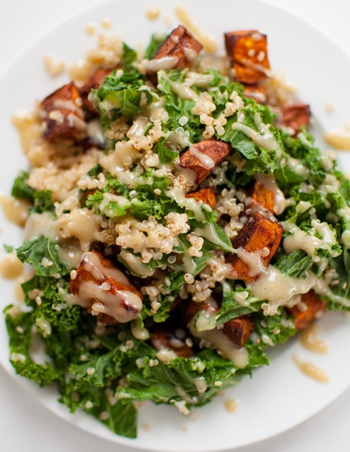 Sweet potato, kale and quinoa come together with a creamy tahini dressing on a plate