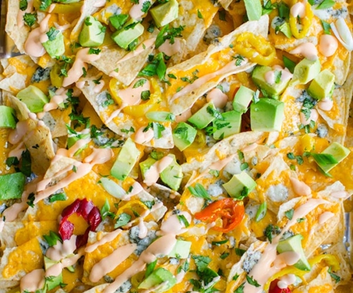 Enjoy all the flavours of Buffalo chicken in this nacho recipe for spicy Buffalo nachos with tons of cheddar and blue cheese, hot peppers and a Buffalo sour cream. | livinglou.com