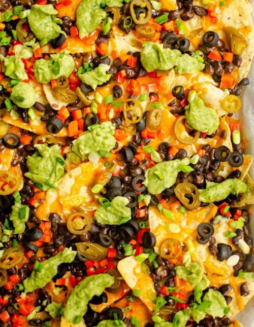 Closeup of vegetarian nachos on a baking sheet.