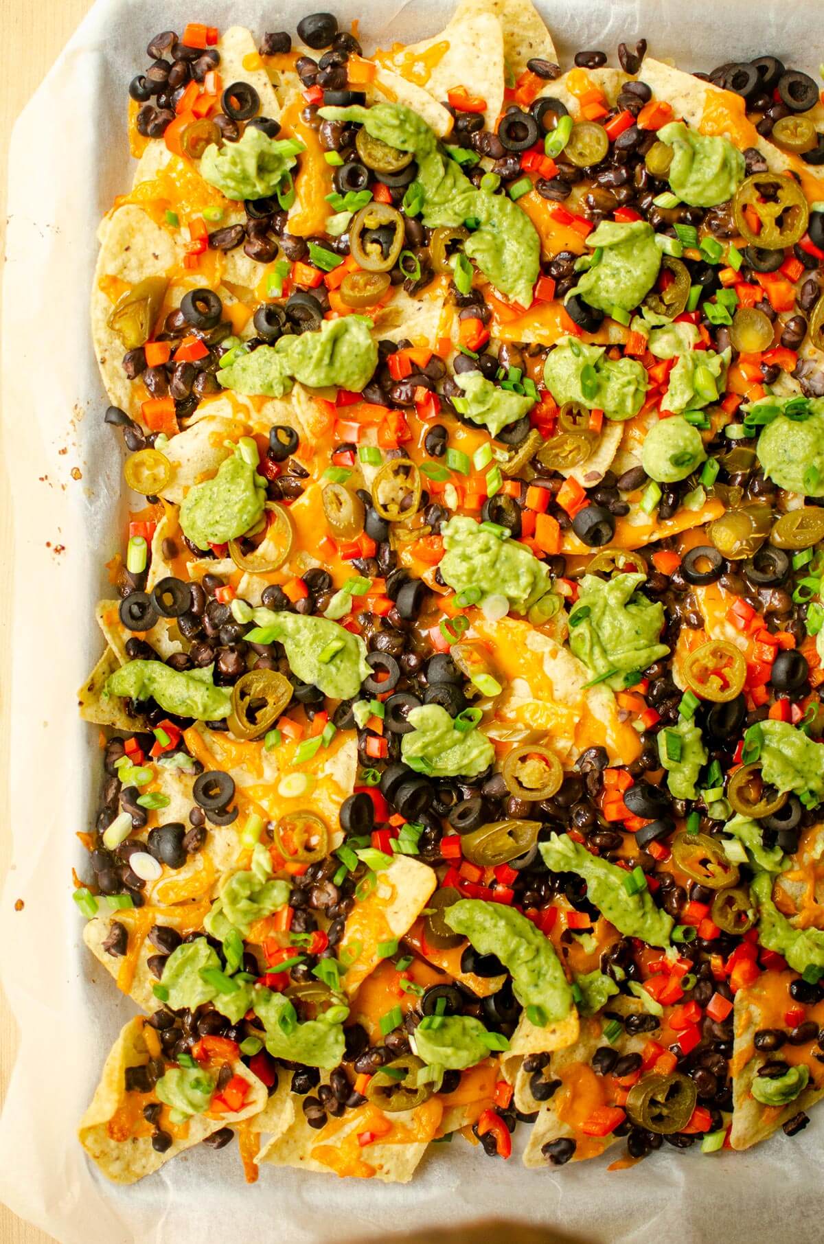 Cooked nachos on sheet pan with all the toppings.