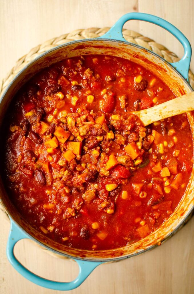 Chili in a turquoise dutch oven with a wooden spoon.