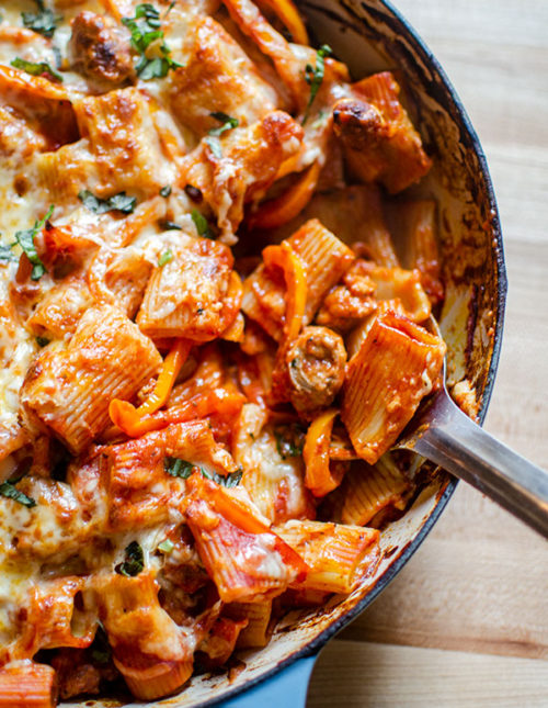 A scoop being taken out of cheesy sausage and pepper pasta