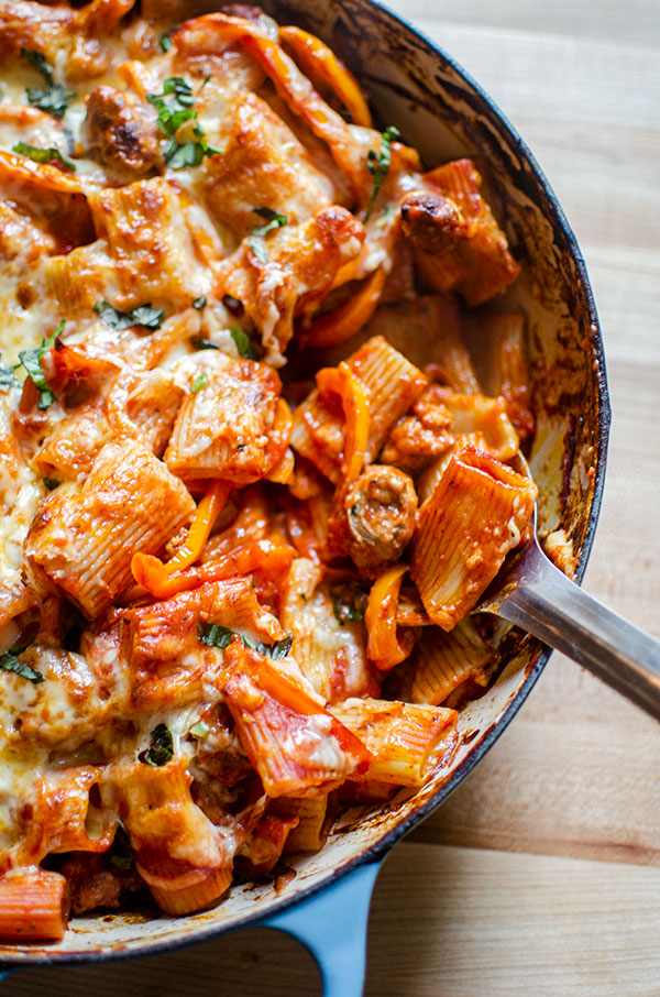 A scoop being taken out of cheesy sausage and pepper pasta