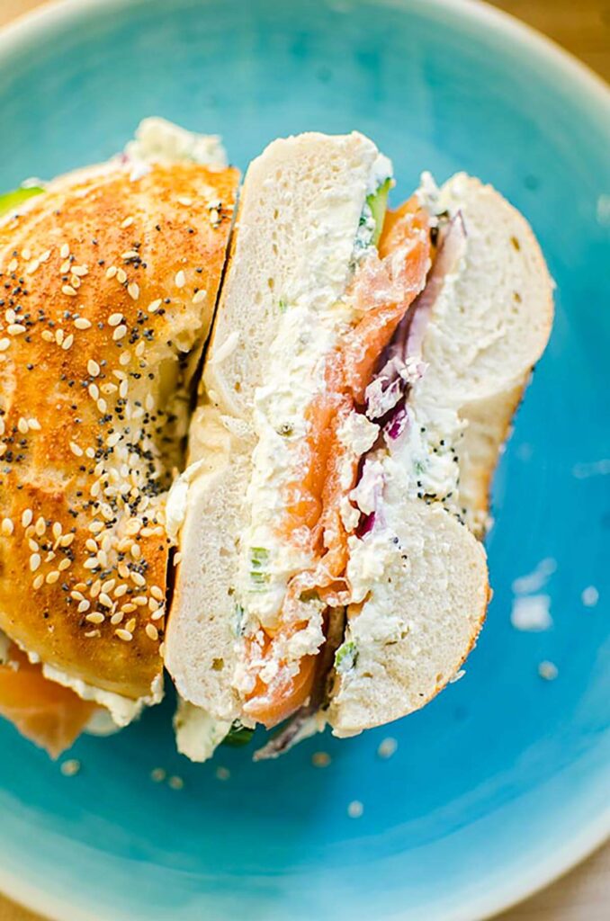 A bagel sliced in half with the cut side facing up on a blue plate. 