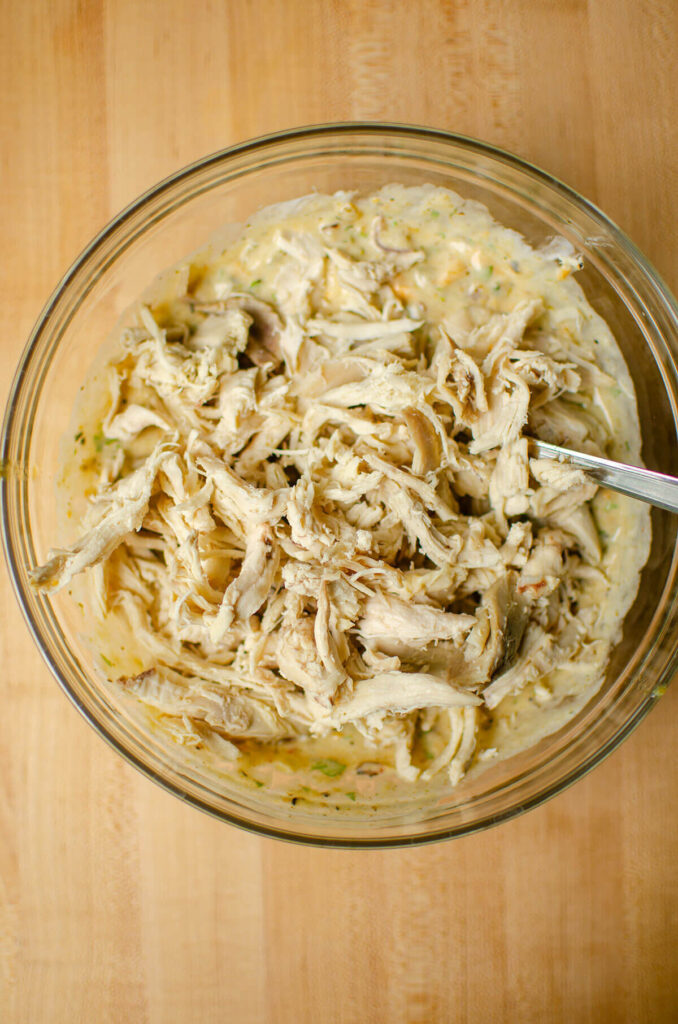 Shredded chicken in a glass bowl with filling sauce.
