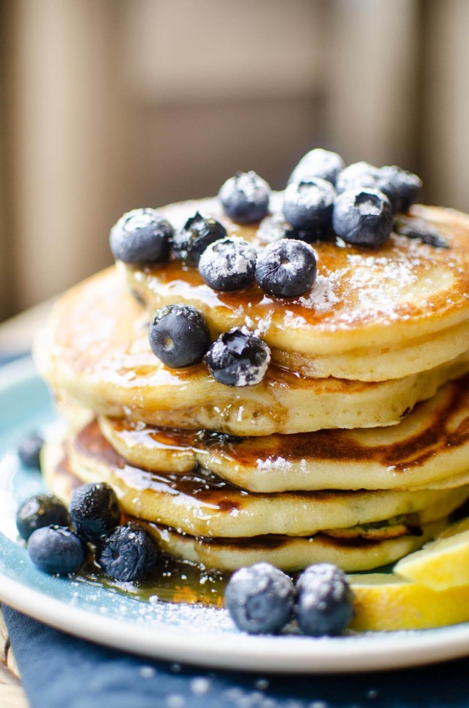 Closeup of a stack of pancakes with blueberries and maple syrup