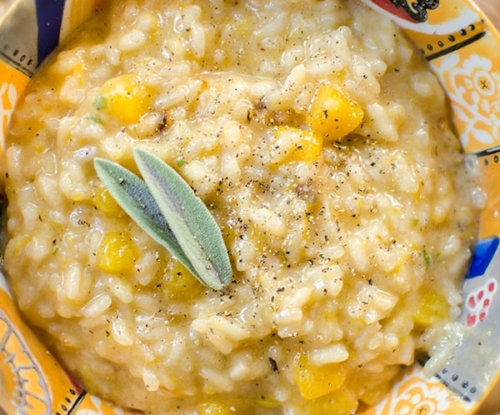 Butternut squash risotto in a colourful bowl with a fresh sage garnish.