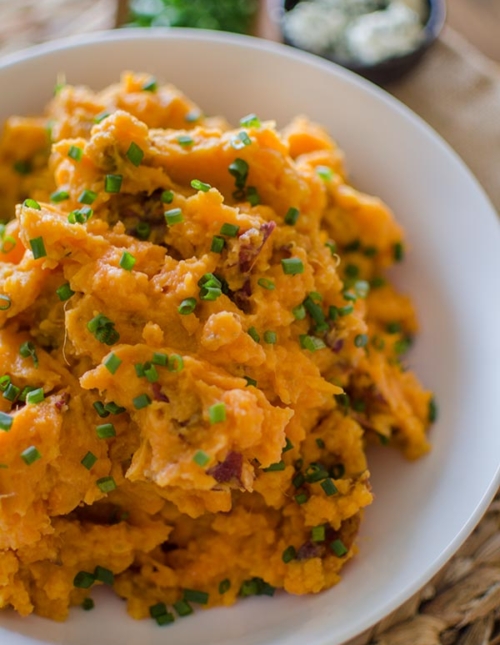 Buttermilk blue cheese mashed potatoes in a white bowl with chives sprinkled on top