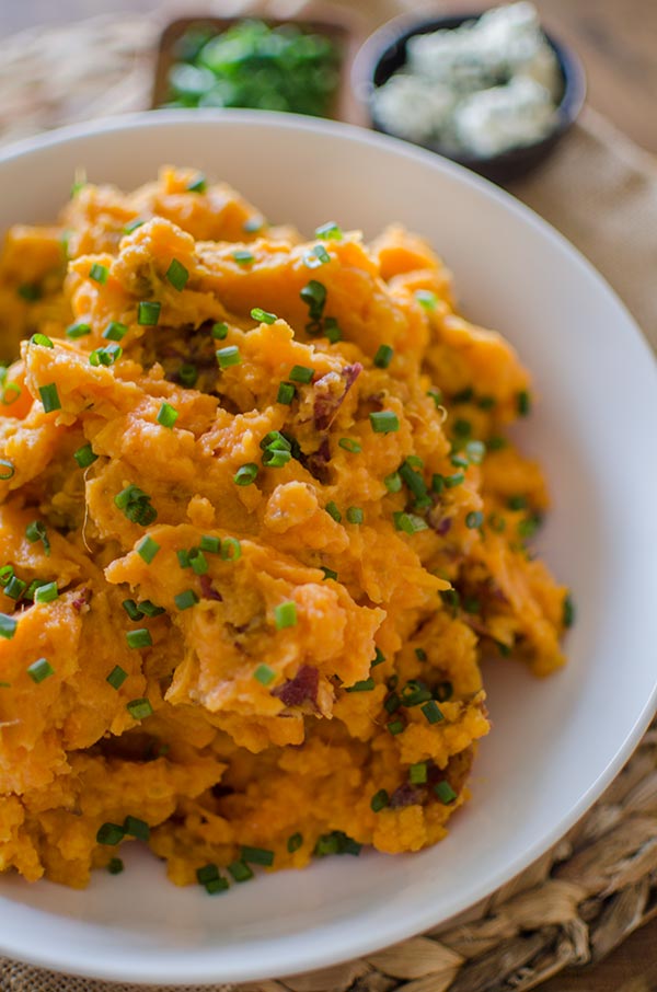 Buttermilk blue cheese mashed potatoes in a white bowl with chives sprinkled on top