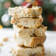 Hazelnut shortbread bars with a chai glaze stacked on top of each other on a plate with a Christmas tree in the background