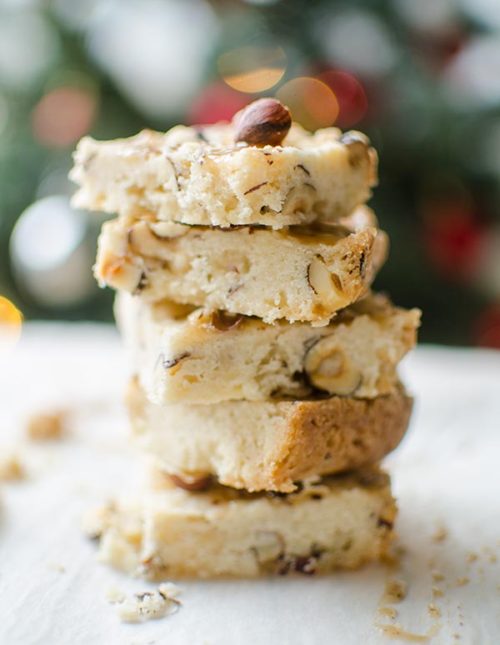 Hazelnut shortbread bars with a chai glaze stacked on top of each other on a plate with a Christmas tree in the background