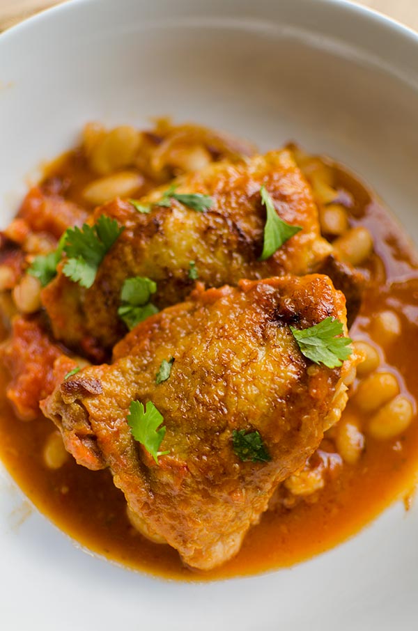 Braised chicken thighs with tomatoes and white beans is a comforting one pot meal made with onions, tomatoes, garlic, white beans  for a savoury delicious dinner.  | livinglou.com