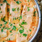 Closeup of salmon fillets in coconut curry sauce with cilantro sprinkled over top.