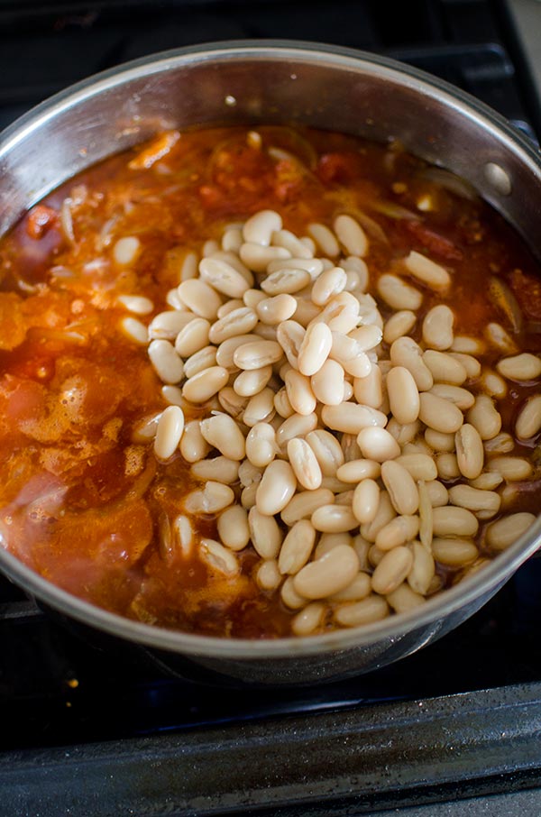 Braised chicken thighs with tomatoes and white beans is a comforting one pot meal made with onions, tomatoes, garlic, white beans  for a savoury delicious dinner.  | livinglou.com