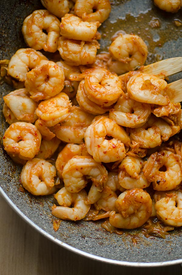 Shrimp marinated in gochujang, fish sauce, garlic and soy sauce stir frying in a skillet.