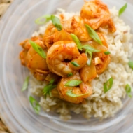 Closeup of shrimp and kimchi stir fry over brown rice with green onions.