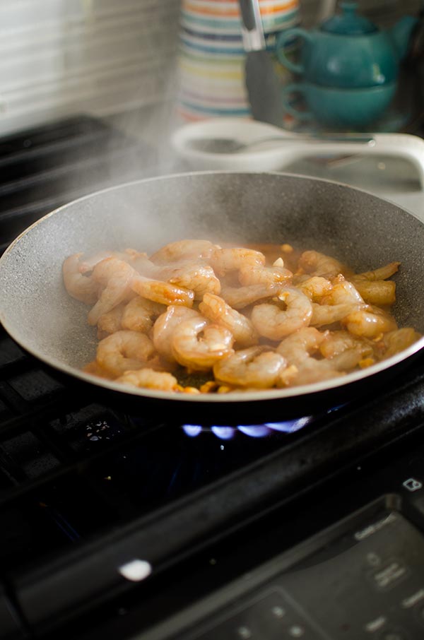 Raw marinated shrimp stir frying in a hot pan.