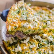 A slice of bacon and asparagus frittata topped with feta.