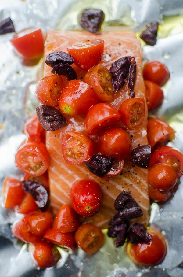 Raw salmon fillet in foil packet with cherry tomatoes and kalamata olives.