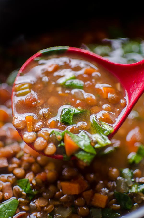 A ladle full of slow cooker lentil and ham soup.