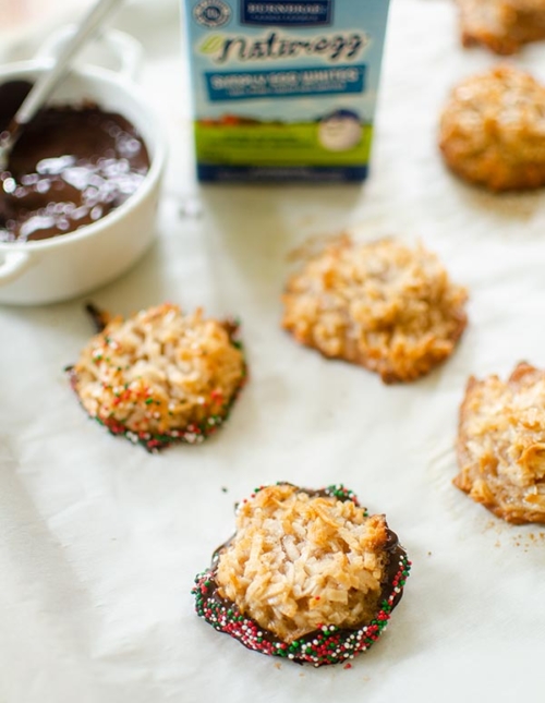 Cinnamon macaroons with the bottoms dipped in chocolate and rolled in sprinkles on a baking sheet.