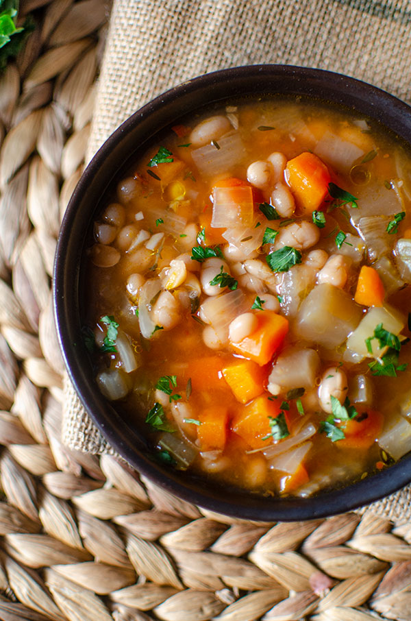 Closeup of navy bean soup in a black bowl.