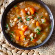 slow cooker navy bean soup in a black bowl with parsley on top