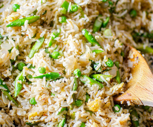 A spoonful of asparagus fried rice in a wok.