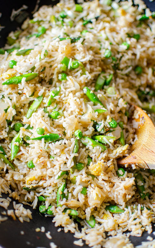 A spoonful of asparagus fried rice in a wok.