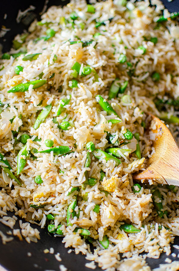 A spoonful of asparagus fried rice in a wok.