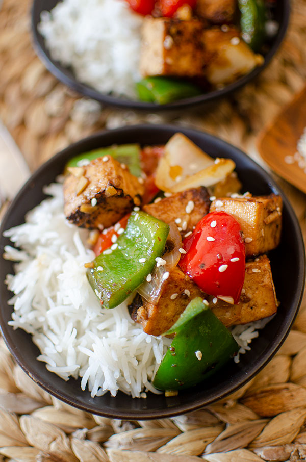 Closeup of tofu stir fry in a black bowl.