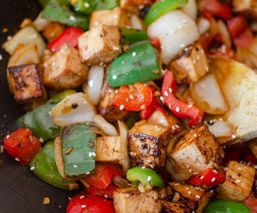 Tofu bell pepper stir fry in a wok.