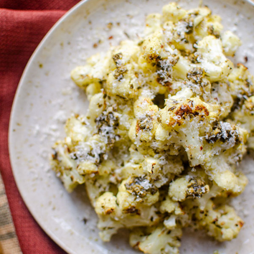 Roasted cauliflower on a plate with parmesan grated on top.