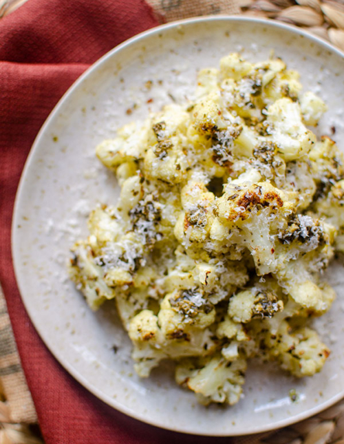 Roasted cauliflower on a plate with parmesan grated on top.