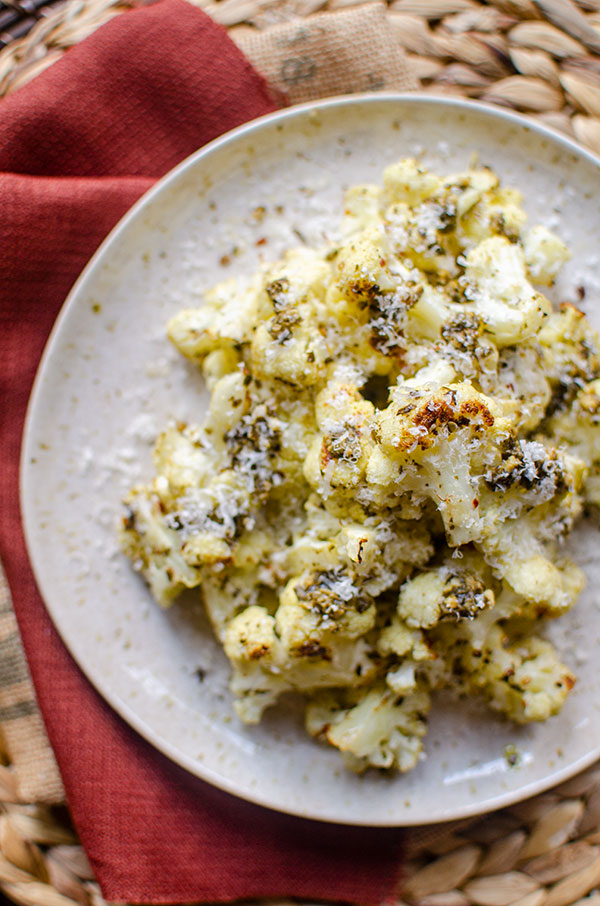 Roasted cauliflower on a plate with parmesan grated on top.