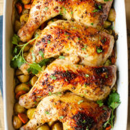 Chicken leg quarters in a 9x14 dish with potatoes and parsley