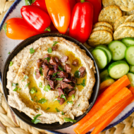 Top down shot of olive hummus in a serving platter.