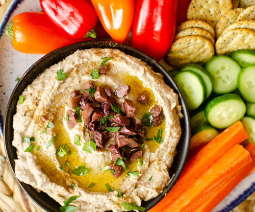 Top down shot of olive hummus in a serving platter.
