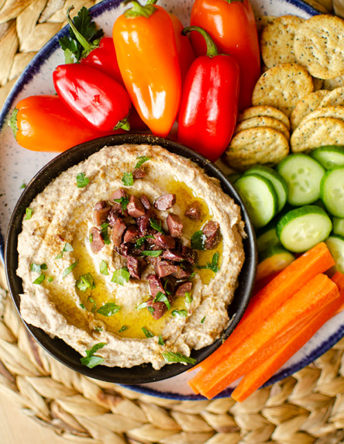 Top down shot of olive hummus in a serving platter.