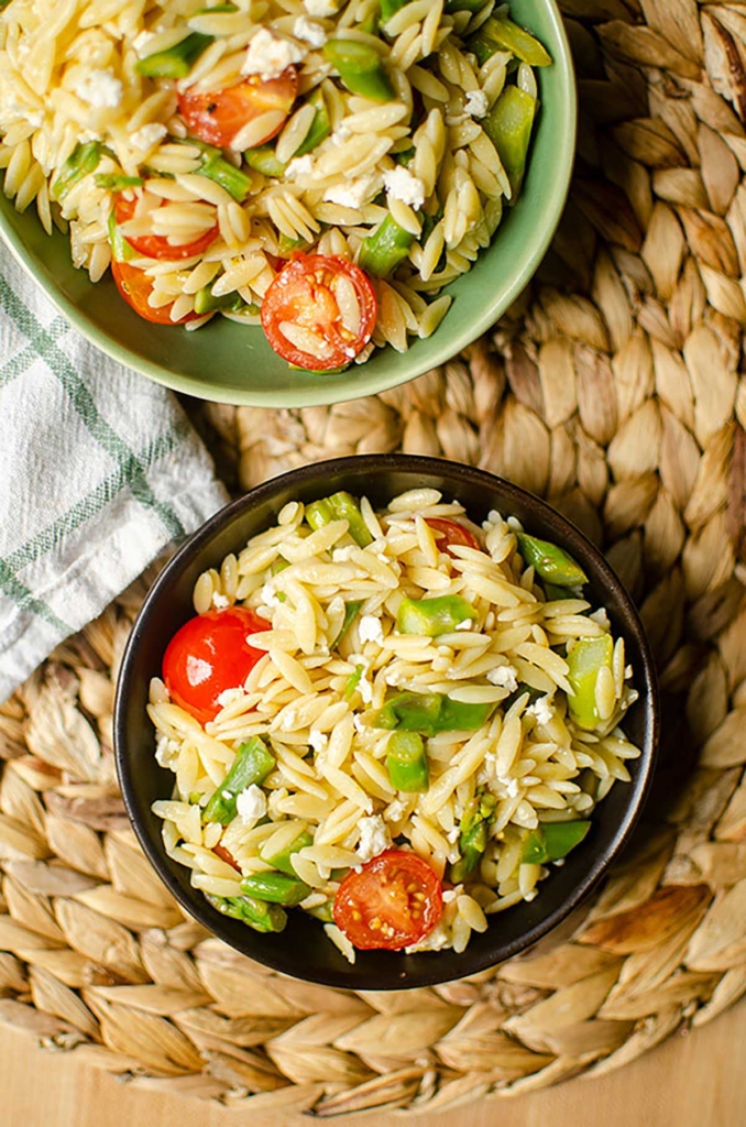 Two servings of lemon orzo one in a black bowl and one in a green bowl