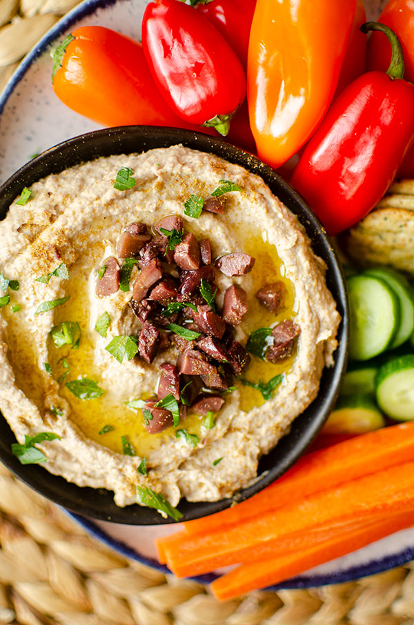 A bowl of hummus on a snack plate.