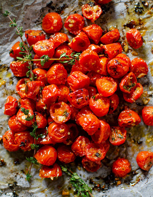 Roasted cherry tomatoes in a pile on a baking sheet