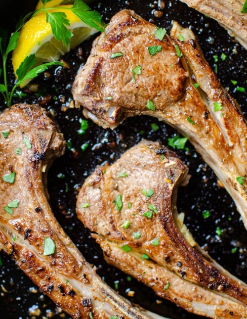 Closeup of finished lamb in a cast iron with parsley and lemon for garnishes
