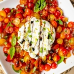 Serving of burrata salad on a white platee.